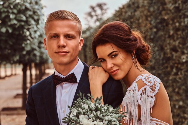 Portrait en gros plan de jeunes mariés - la charmante mariée a posé sa tête sur son beau marié dans le parc.