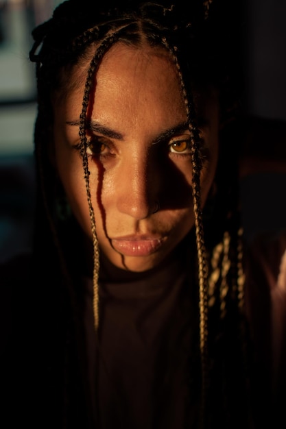 Photo gratuite portrait en gros plan d'une jolie femme hispanique avec de longs cheveux tressés et un rayon de soleil sur son visage