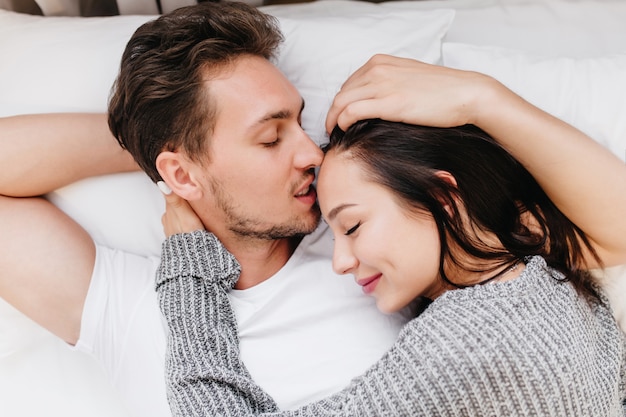 Portrait de gros plan de jolie femme en pyjama gris se trouve dans son lit avec son mari