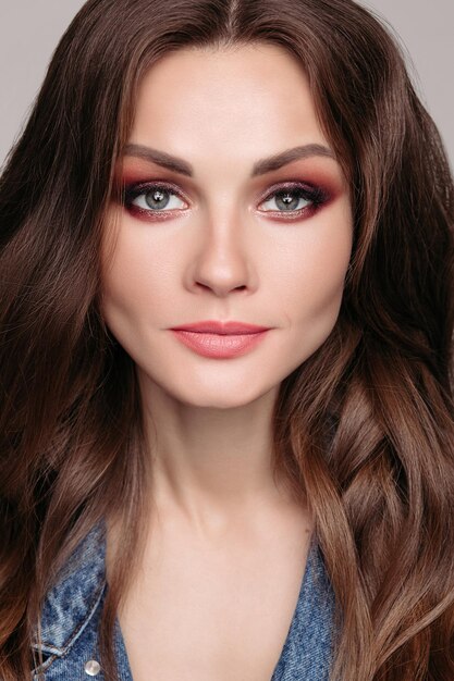 Portrait en gros plan d'une magnifique jolie brune caucasienne jeune femme aux yeux charbonneux brillants et à la peau parfaite regardant la caméra