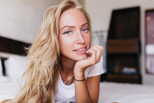 Portrait en gros plan d'une merveilleuse fille blanche aux yeux d'un bleu profond Photo intérieure d'une dame bronzée débonnaire qui se refroidit à la maison