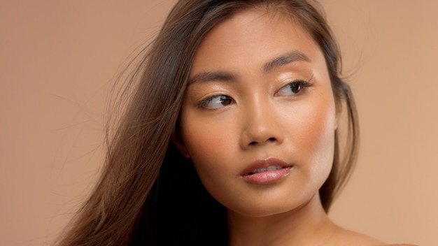 Portrait en gros plan d'un modèle japonais thaïlandais asiatique se tenant de côté avec les cheveux soufflant