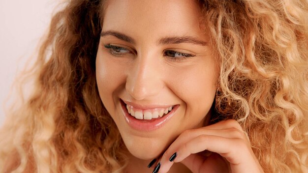 Portrait en gros plan d'un regard coquin souriant heureux d'un modèle blond avec une peau idéale et des cheveux cyrly