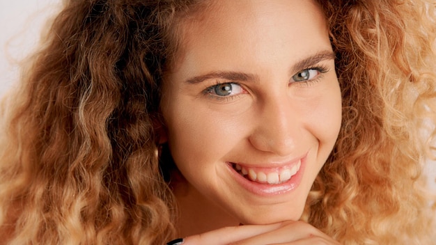 Portrait en gros plan d'un regard coquin souriant heureux d'un modèle blond avec une peau idéale et des cheveux cyrly