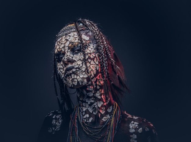 Portrait en gros plan d'une sorcière de la tribu africaine indigène, vêtue d'un costume traditionnel. Notion de maquillage. Isolé sur un fond sombre.
