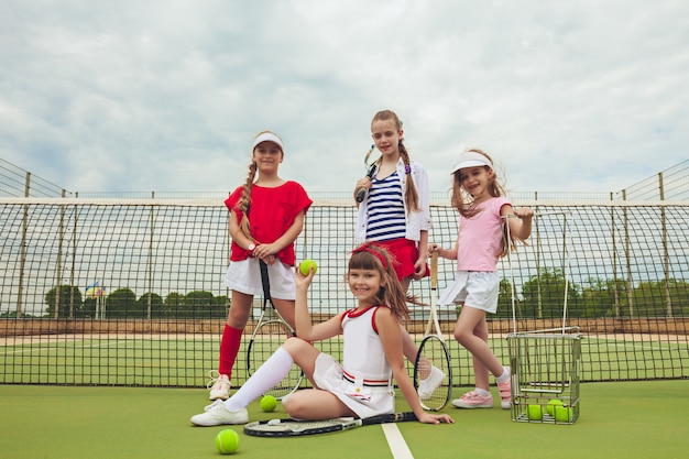 Portrait de groupe de filles en tant que joueurs de tennis tenant une raquette de tennis contre l'herbe verte de la cour extérieure