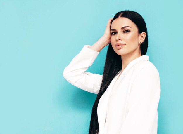 Portrait de haute couture de jeune belle femme brune vêtue d'un beau costume blanc à la mode Mannequin sexy posant en studio Femme à la mode isolée sur bleu