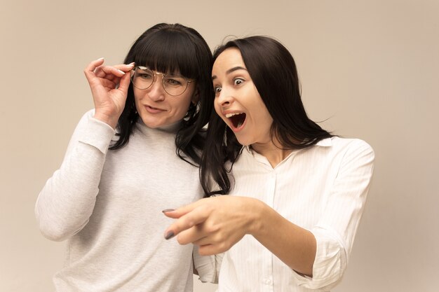 Un portrait d'une heureuse mère et fille surprise au studio sur fond gris