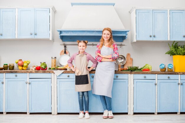 Portrait de l&#39;heureuse mère et fille en tablier debout dans la cuisine