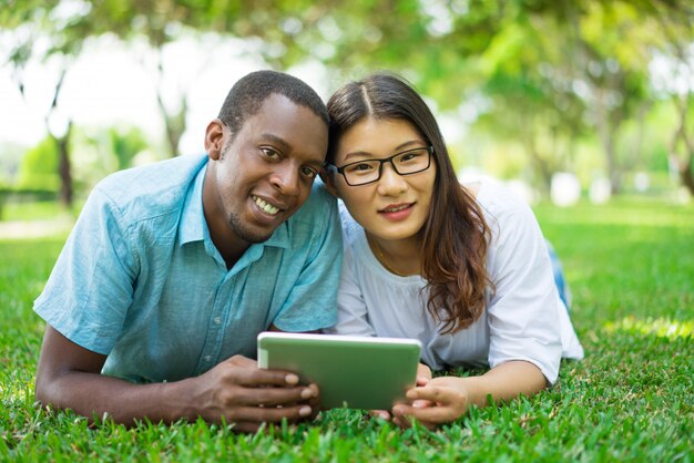 Portrait de l&#39;heureux couple multiethnique avec tablette numérique dans le parc.