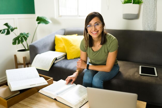 Portrait d'un heureux mi-adulte souriant et regardant la caméra tout en étudiant pour les tests universitaires