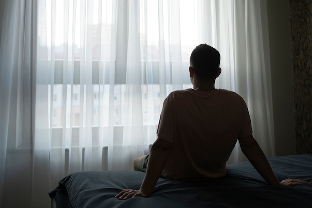 Portrait d'un homme adulte avec rideaux et ombre depuis la fenêtre