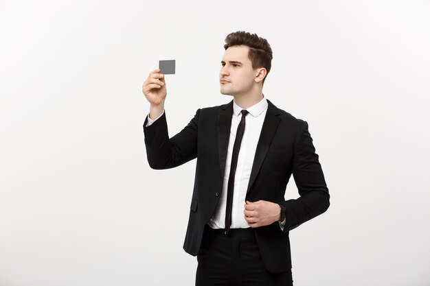 Portrait d'un homme d'affaires détenant une carte de crédit et vérifiant sérieusement isolé sur fond gris.