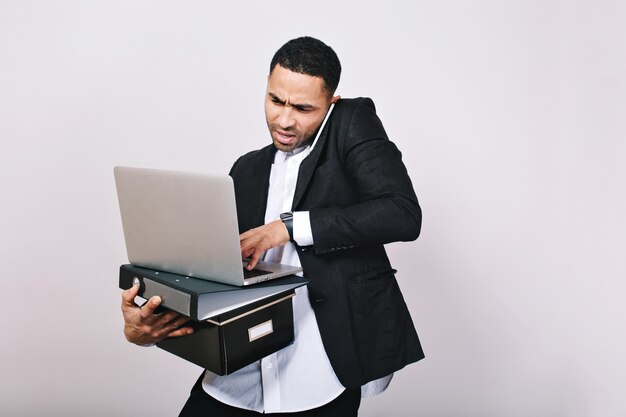 Portrait d'homme d'affaires étonné de travail acharné avec dossiers de bureau, ordinateur portable, parler au téléphone. Employé de bureau, carrière, malentendu, bel homme intelligent.