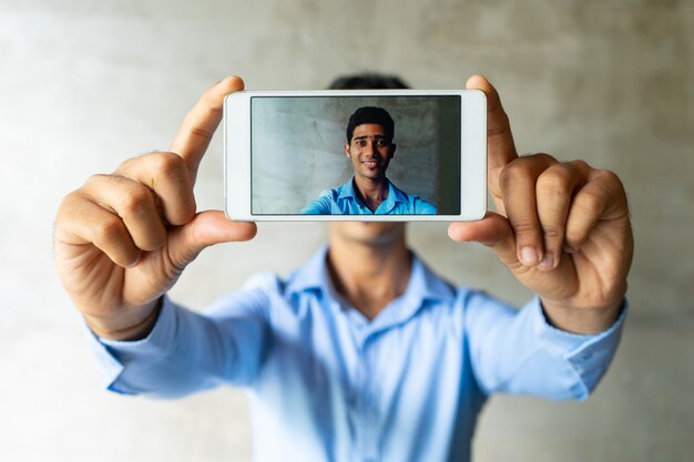 Portrait d&#39;homme d&#39;affaires souriant prenant selfie avec smartphone.