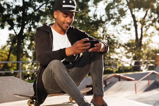 Portrait d'un homme africain heureux à l'aide de téléphone portable