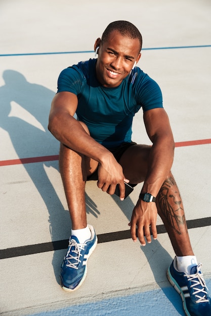 Photo gratuite portrait d'un homme africain de remise en forme motivé souriant dans les écouteurs