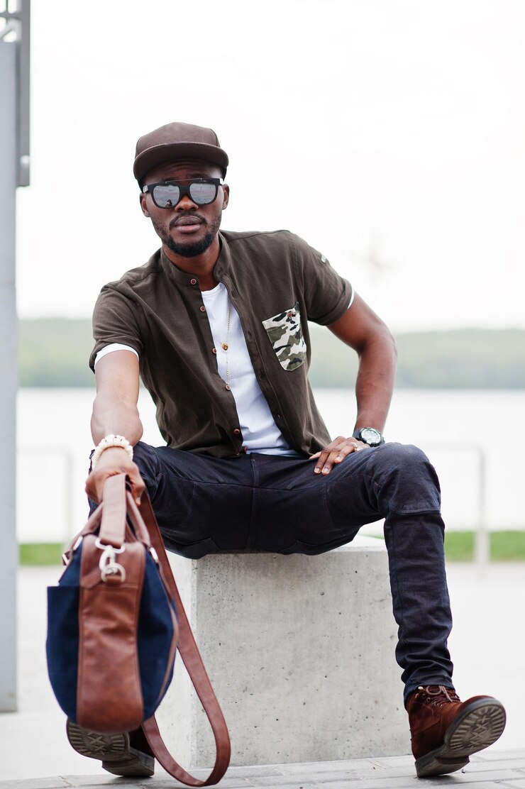 Photo gratuit portrait d'un homme afro-américain élégant assis portant des lunettes de soleil et une casquette en plein air street fashion black man