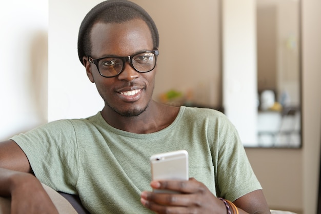 Portrait d'un homme afro-américain élégant avec smartphone à la maison