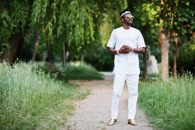 Portrait d'un homme afro-américain noir élégant et riche sur des lunettes de soleil et un chapeau de vêtements blancs