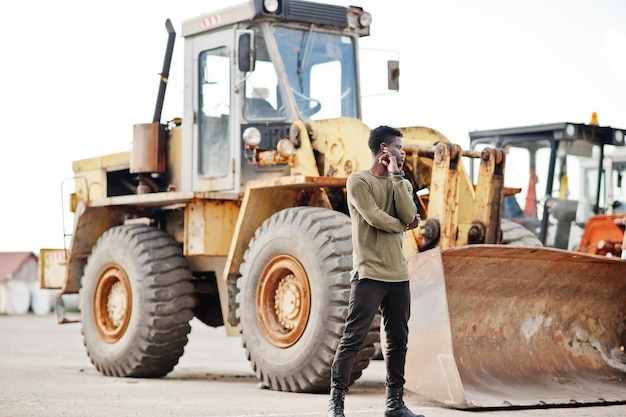 Portrait d'un homme afro-américain noir séduisant posant à côté de la machinerie industrielle