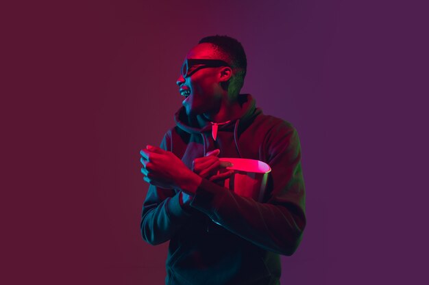 Portrait de l'homme afro-américain qui rit sur un studio dégradé à la lumière du néon