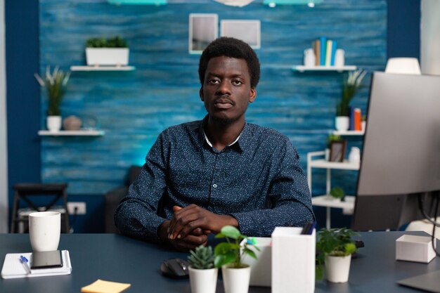 Portrait d'un homme afro-américain regardant la caméra au bureau jeune homme noir assis dans un cadre moderne et confortable ...