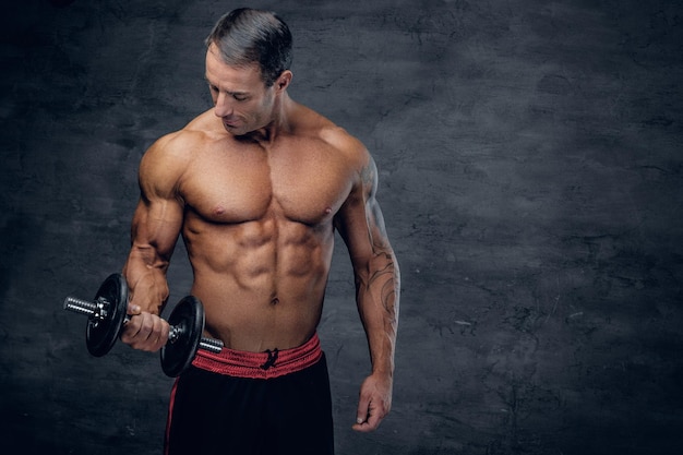 Portrait d'un homme d'âge moyen athlétique et musclé torse nu tenant une haltère.