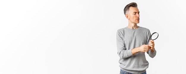 Photo gratuite portrait d'un homme d'âge moyen réfléchi regardant à travers une loupe à la recherche de quelque chose ou re