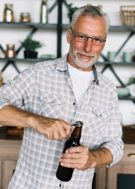 Portrait d&#39;un homme âgé ouvrant la bouteille de bière avec ouvre