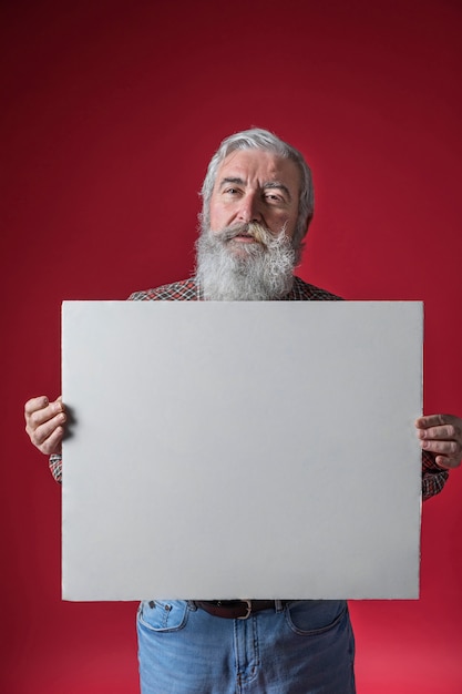 Portrait, de, a, homme aîné, projection, vierge, blanc, plaque, debout, contre, toile de fond rouge