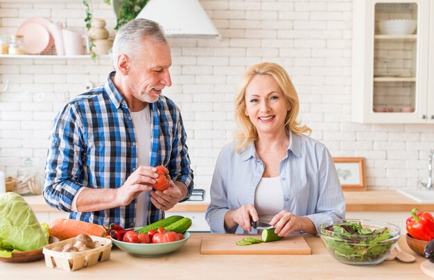 Portrait, homme aîné, regarder, femme, couper, légume, moderne, cuisine