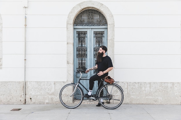 Photo gratuite portrait d'un homme assis sur un vélo devant la porte bleue