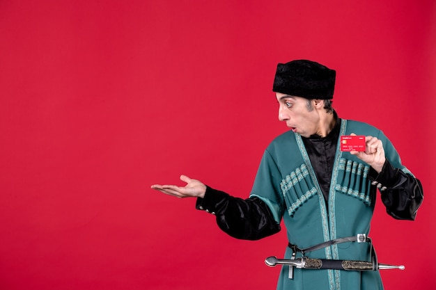 Photo gratuite portrait d'un homme azéri en costume traditionnel tenant une carte de crédit sur l'argent du printemps rouge novruz ethnique