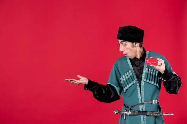 Portrait d'un homme azéri en costume traditionnel tenant une carte de crédit sur l'argent du printemps rouge novruz ethnique