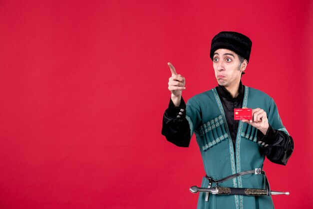 Portrait d'un homme azéri en costume traditionnel tenant une carte de crédit studio shot rouge novruz printemps argent ethnique