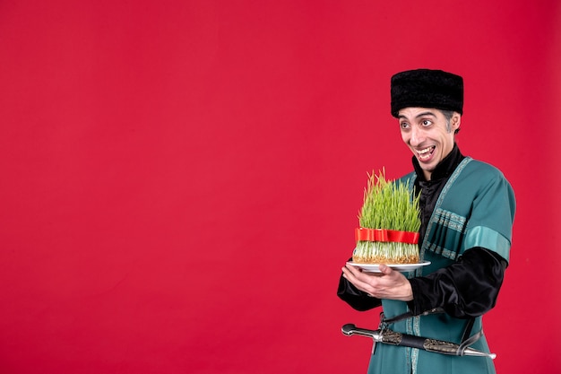 Portrait d'un homme azéri en costume traditionnel tenant un semeni vert sur des vacances ethniques danseuse rouge novruz