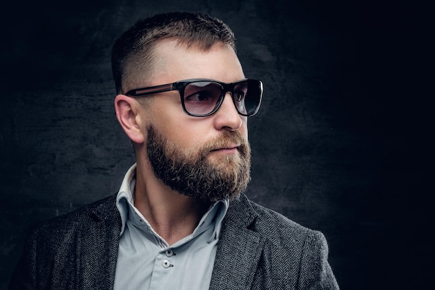 Portrait d'un homme barbu d'âge moyen portant des lunettes de soleil et une veste en laine de ver.