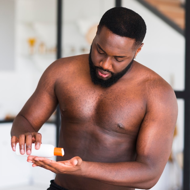 Portrait d'homme barbu à l'aide d'une crème hydratante