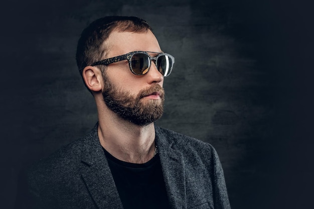 Portrait d'homme barbu en costume et lunettes de soleil.