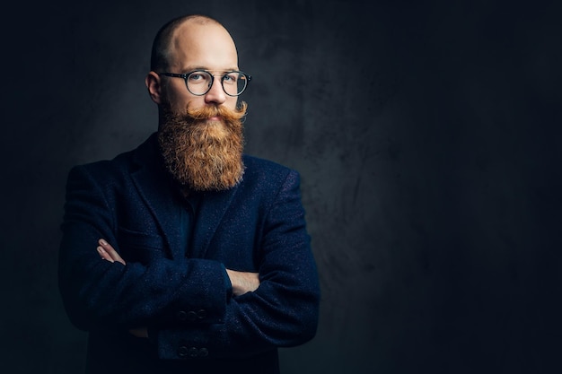 Photo gratuite portrait d'homme barbu rousse à lunettes vêtu d'un élégant costume de laine sur fond gris.