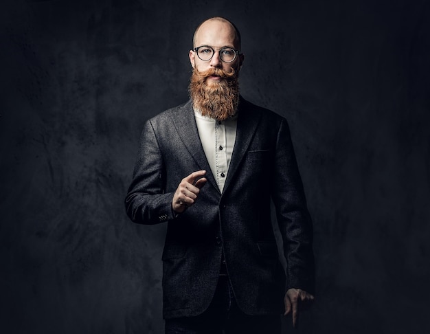 Photo gratuite portrait d'homme barbu rousse à lunettes vêtu d'un élégant costume de laine sur fond gris.