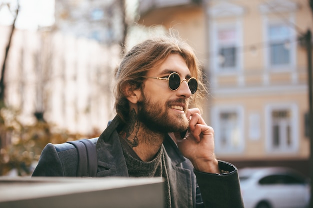 Portrait d'un homme barbu souriant à lunettes de soleil