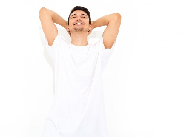 Portrait d'un homme beau jeune mannequin souriant vêtu de jeans et T-shirt posant. Toucher sa tête