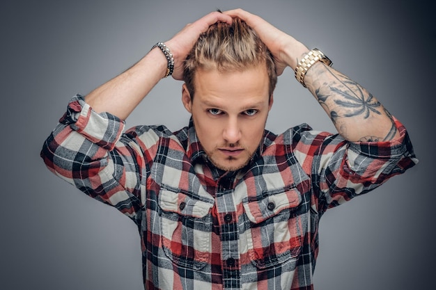 Photo gratuite portrait d'un homme blond aux bras tatoués sur la tête vêtu d'une chemise à carreaux isolée sur fond de vignette grise.