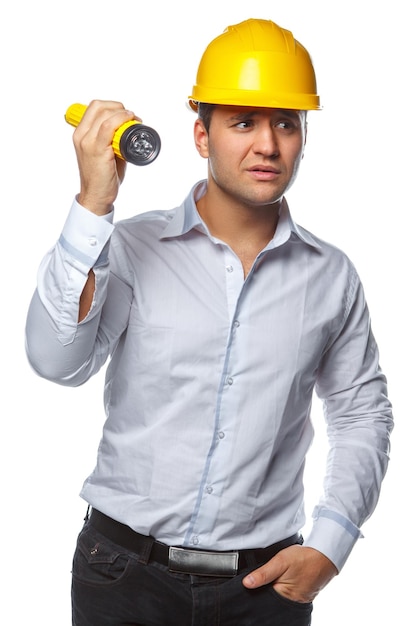 Portrait d'homme en casque de sécurité jaune et lampe de poche sur fond blanc.