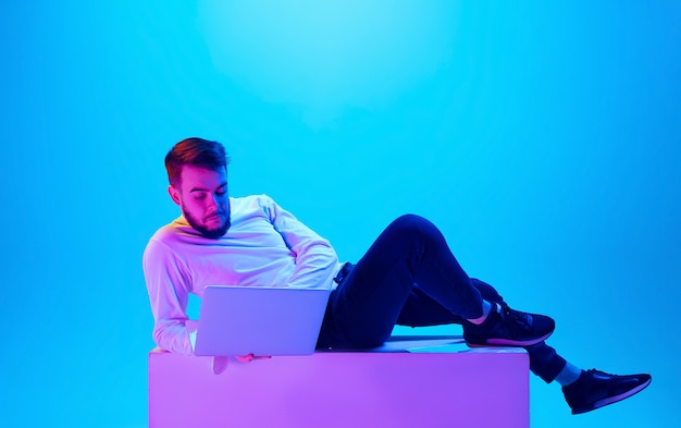 Portrait de l'homme caucasien isolé sur fond bleu studio en néon. Beau modèle masculin. Concept d'émotions humaines, expression faciale, ventes, publicité. Copyspace pour l'annonce.