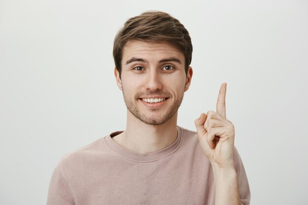 Portrait d'un homme caucasien mature et séduisant avec un joli visage levant l'index et pointant vers le haut ou montrant le numéro un