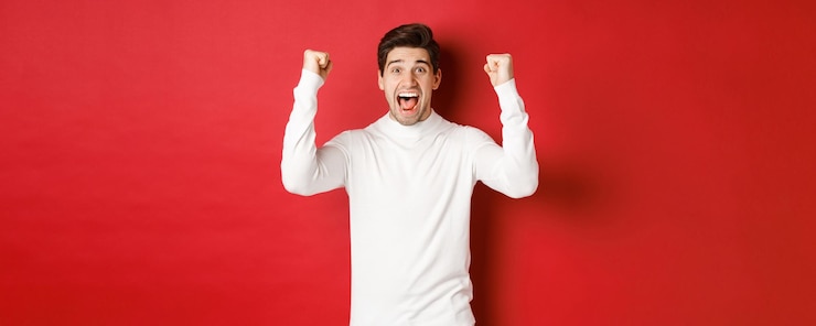 Photo gratuit portrait d'un homme chanceux excité en pull blanc levant les mains et triomphant en célébrant le nouvel an ...