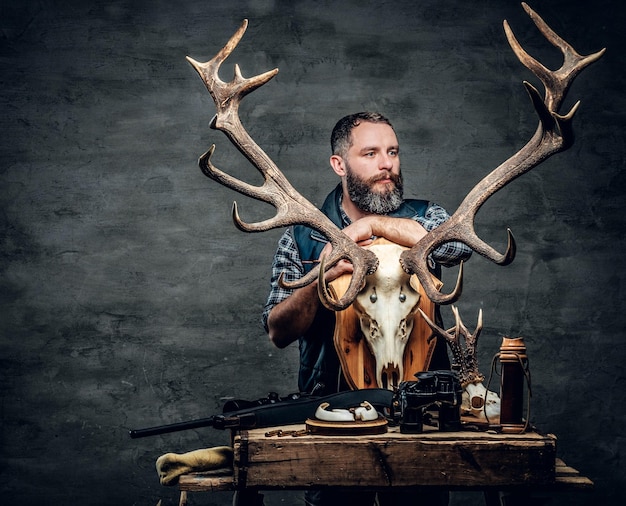 Le portrait d'un homme chasseur tient un crâne de cerf.